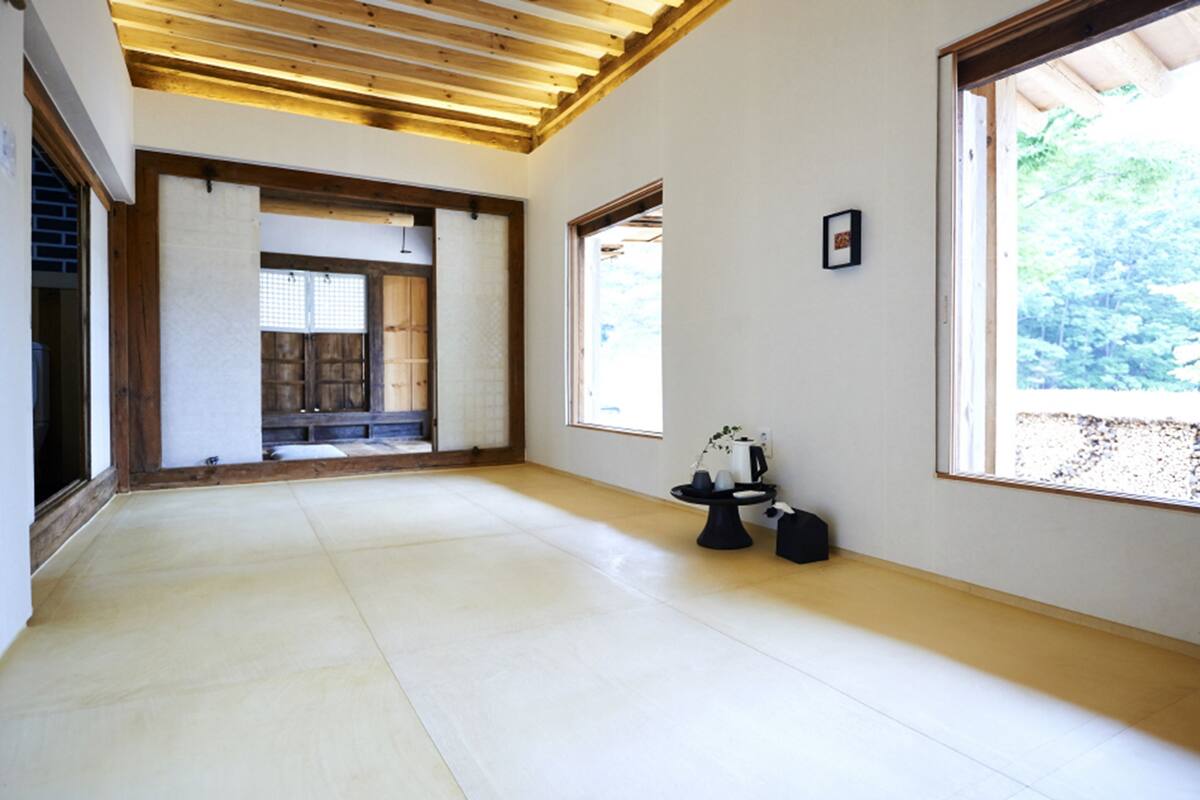 A spacious room with tatami flooring, a traditional sliding door, and a view of greenery outside.
