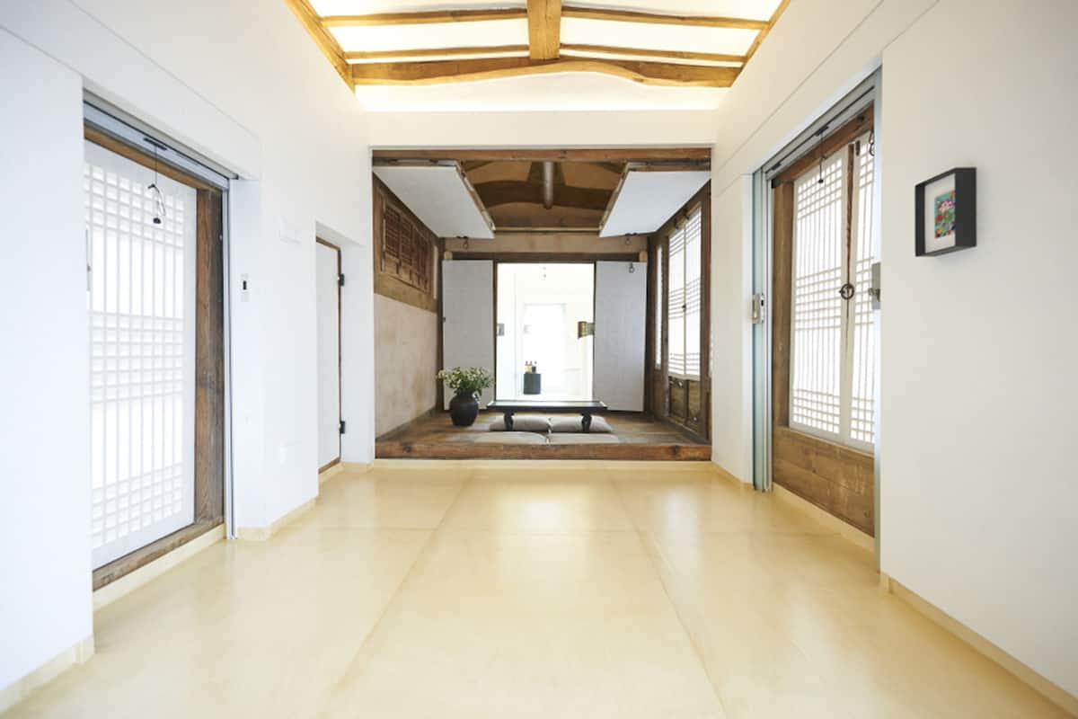 A corridor with wooden flooring, a bench, and a door at the end.
