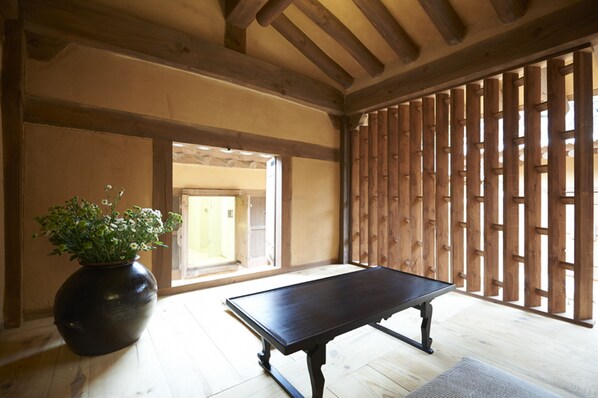 A traditional Japanese room with tatami flooring, a low wooden table, and a large black vase with flowers.