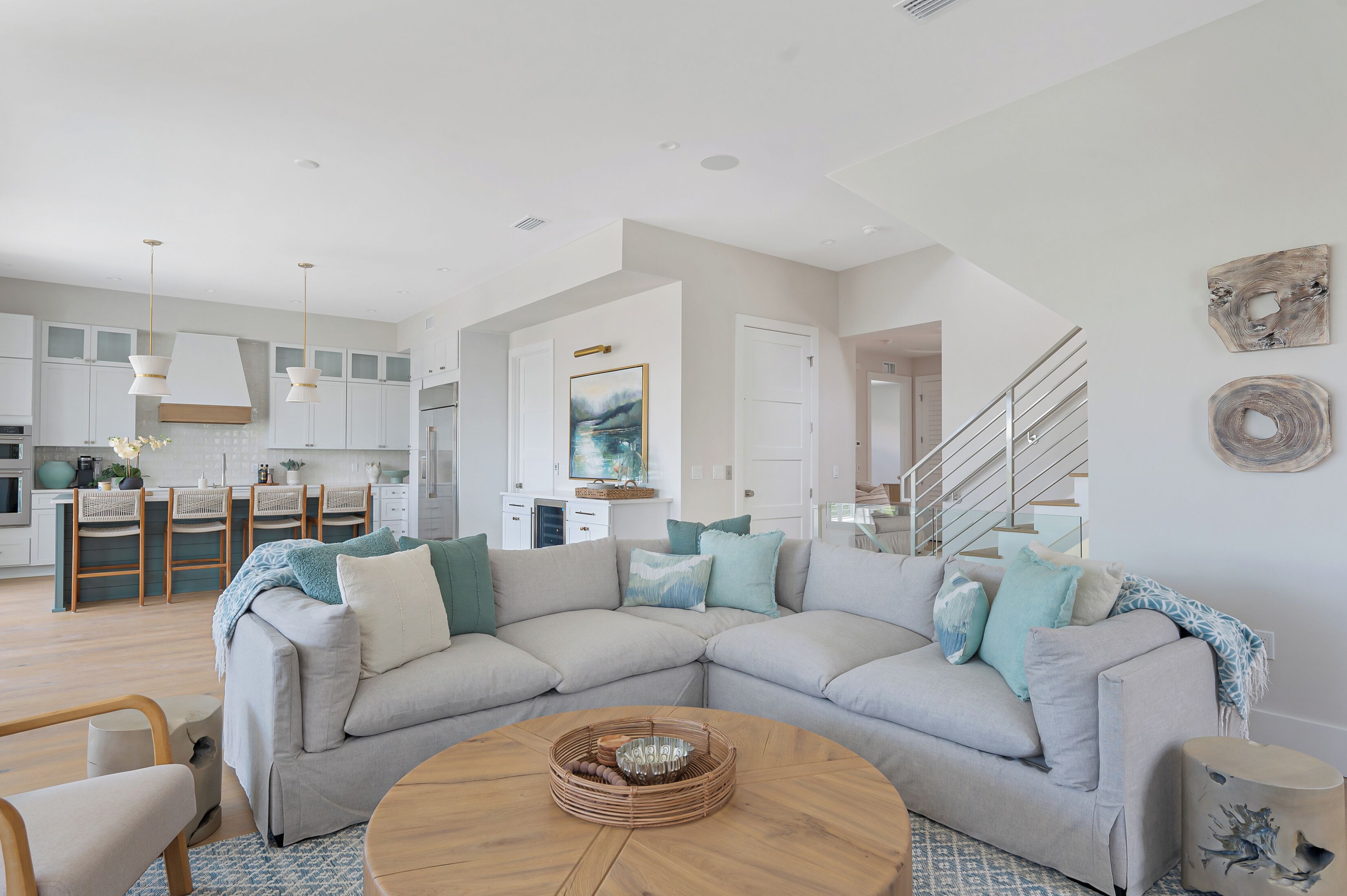 A modern living room with a sectional sofa, a round coffee table, and a kitchen in the background.