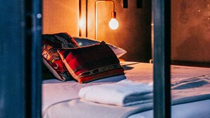 A hotel room with a bed, pillows, a bedside lamp, and a window. - Native Hostel Austin (Austin)