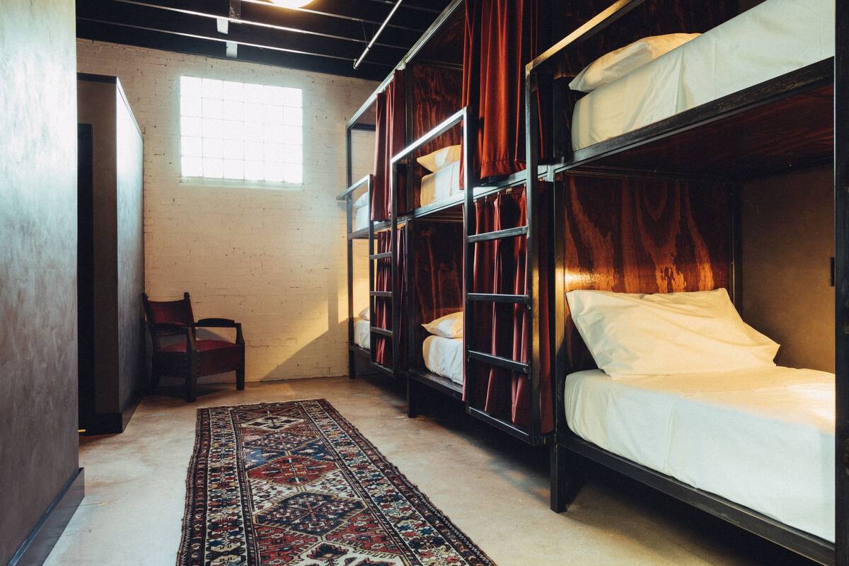 Um quarto com beliches, uma cadeira e um tapete estampado.