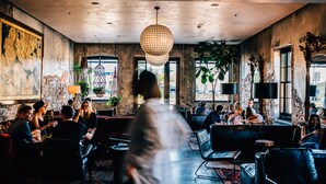 A modern interior with a large chandelier, seating areas, and large windows. - Native Hostel Austin (Austin)