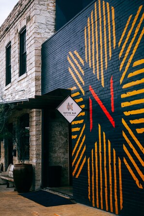 A building with a brick facade and a large mural with yellow and red lines.