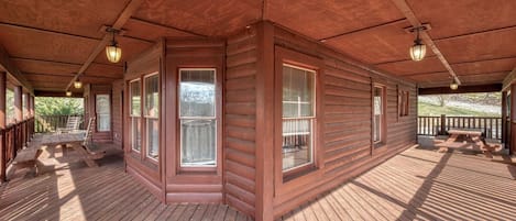 Relax on the covered deck with a picnic table and benches, surrounded by natural light and cozy ambiance.