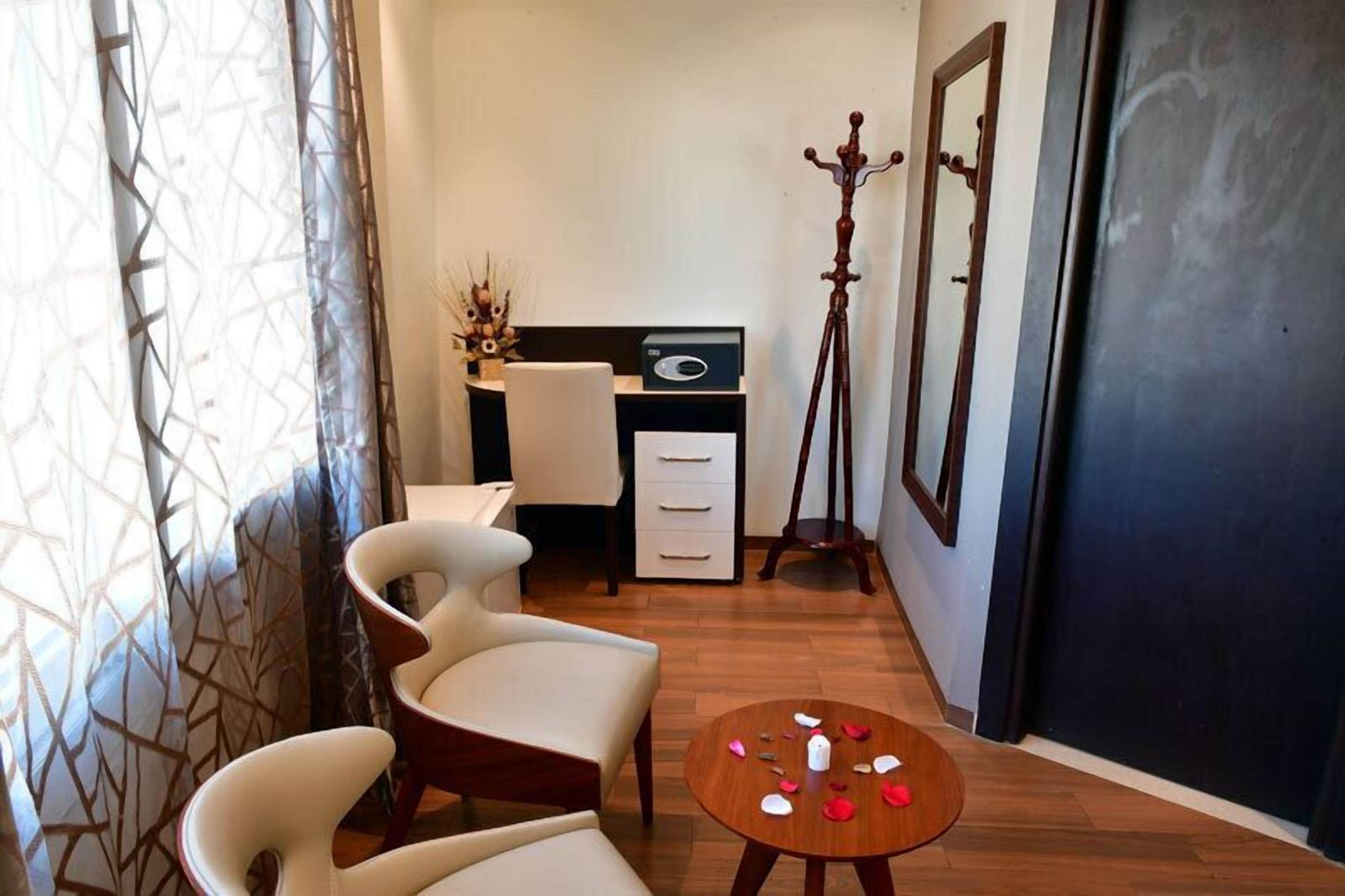 Una habitación con un escritorio, dos sillas, un trípode y una pequeña mesa con objetos desparramados.