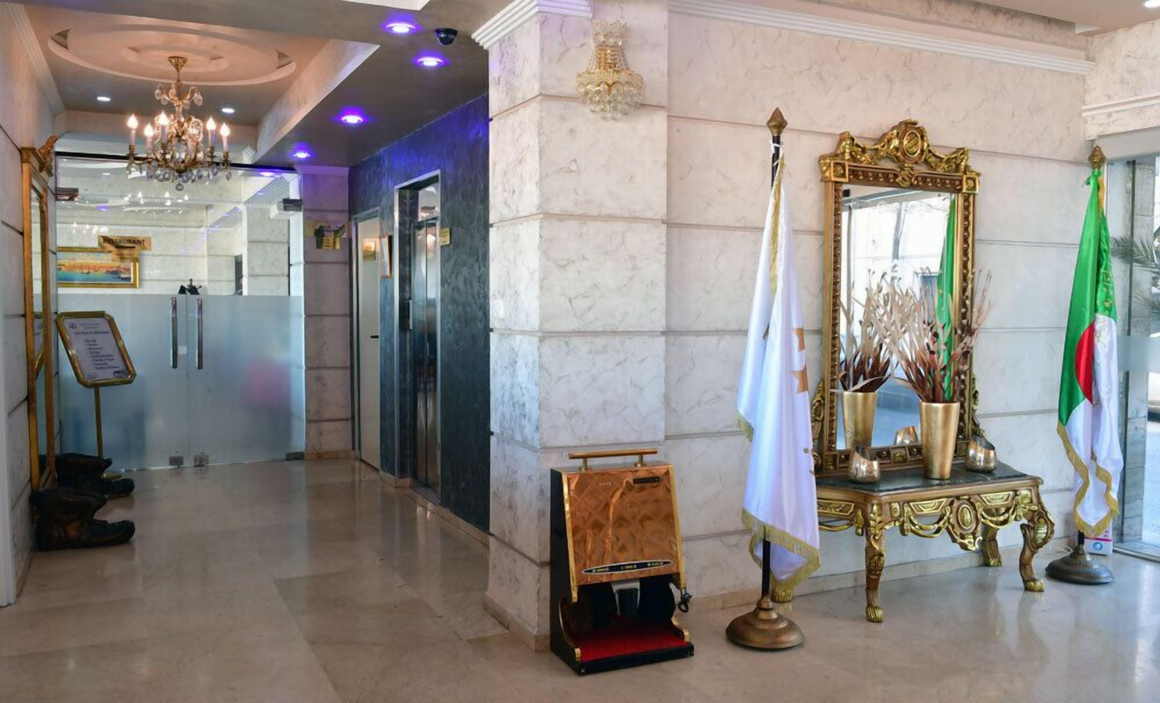 Un hall d’entrée agrémenté d’un lustre, d’un miroir, de drapeaux et d’un comptoir de réception.