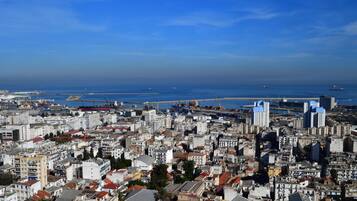 A coastal cityscape with dense urban buildings, a marina, and a clear blue sky.