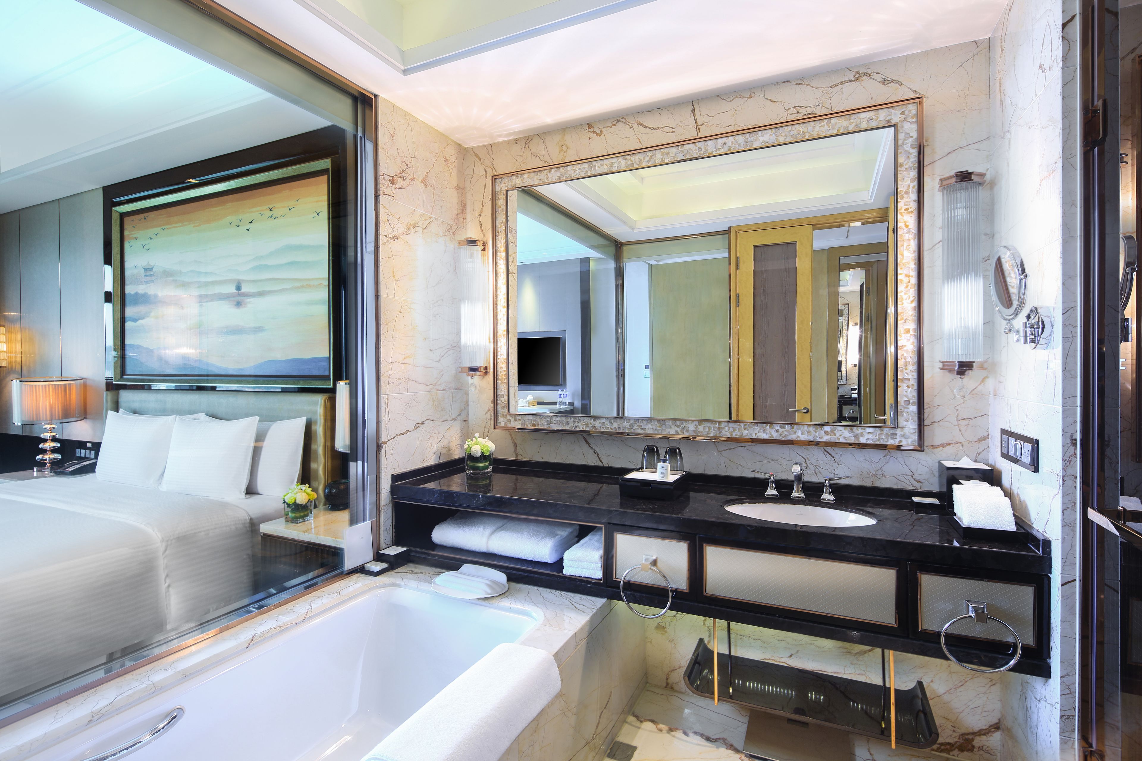 A modern hotel bathroom with a large bathtub, a double sink vanity, and a large mirror.