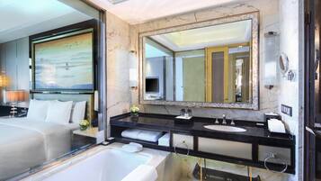 A modern hotel bathroom with a large bathtub, a double sink vanity, and a large mirror.