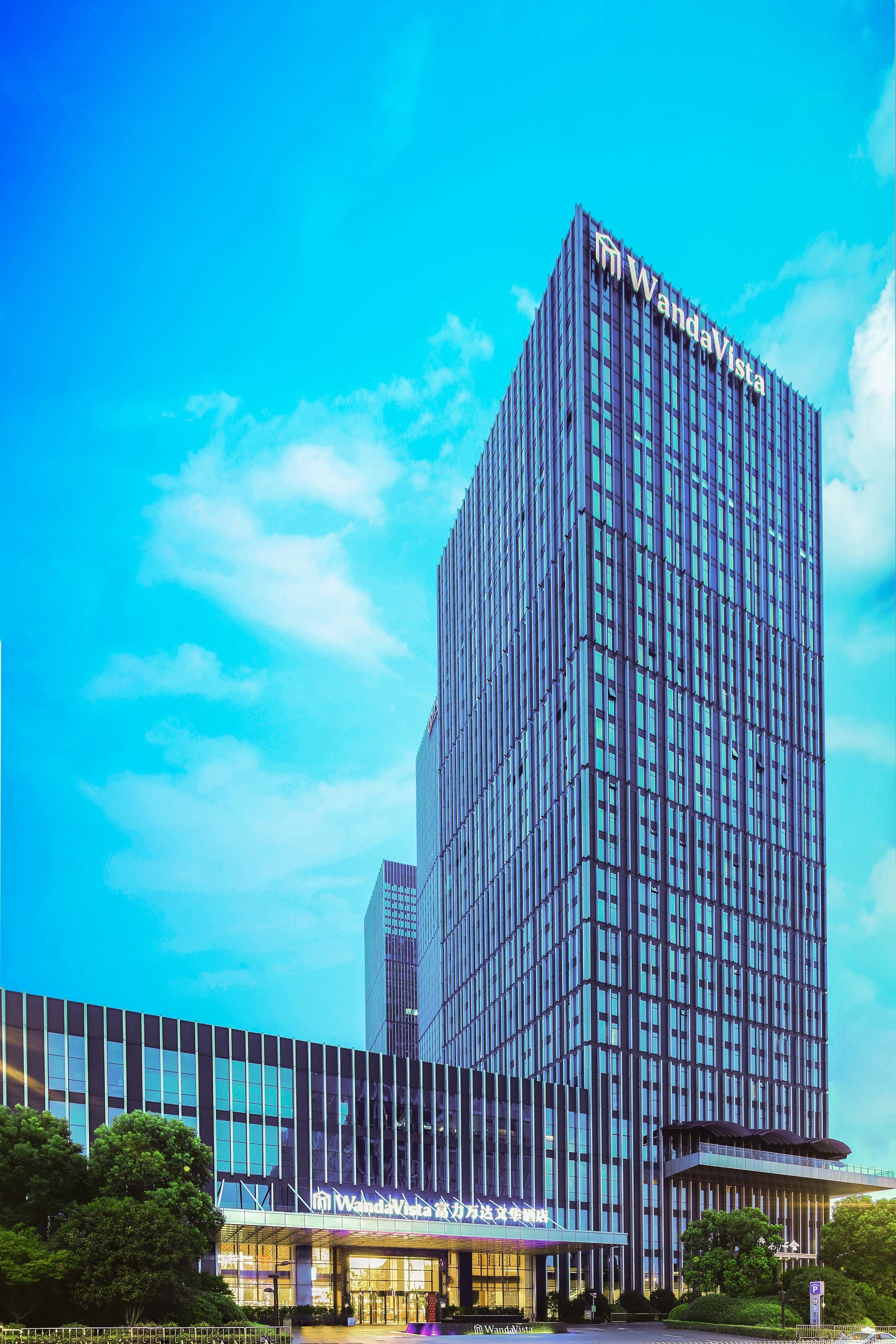 A modern high-rise hotel with a prominent 'WandaVista' sign, featuring a glass facade and a structured, vertical design.