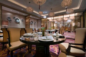 A dining area with round tables, chairs, and hanging chandeliers. - Wanda Vista Changsha (Changsha)