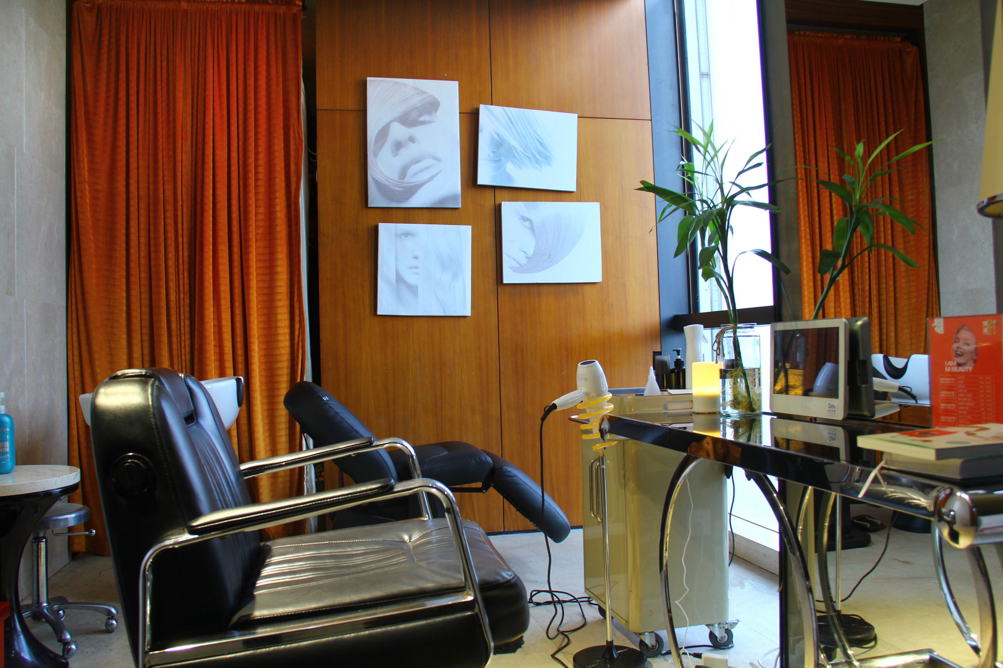 A room with a massage chair, a desk with a computer, and a plant.