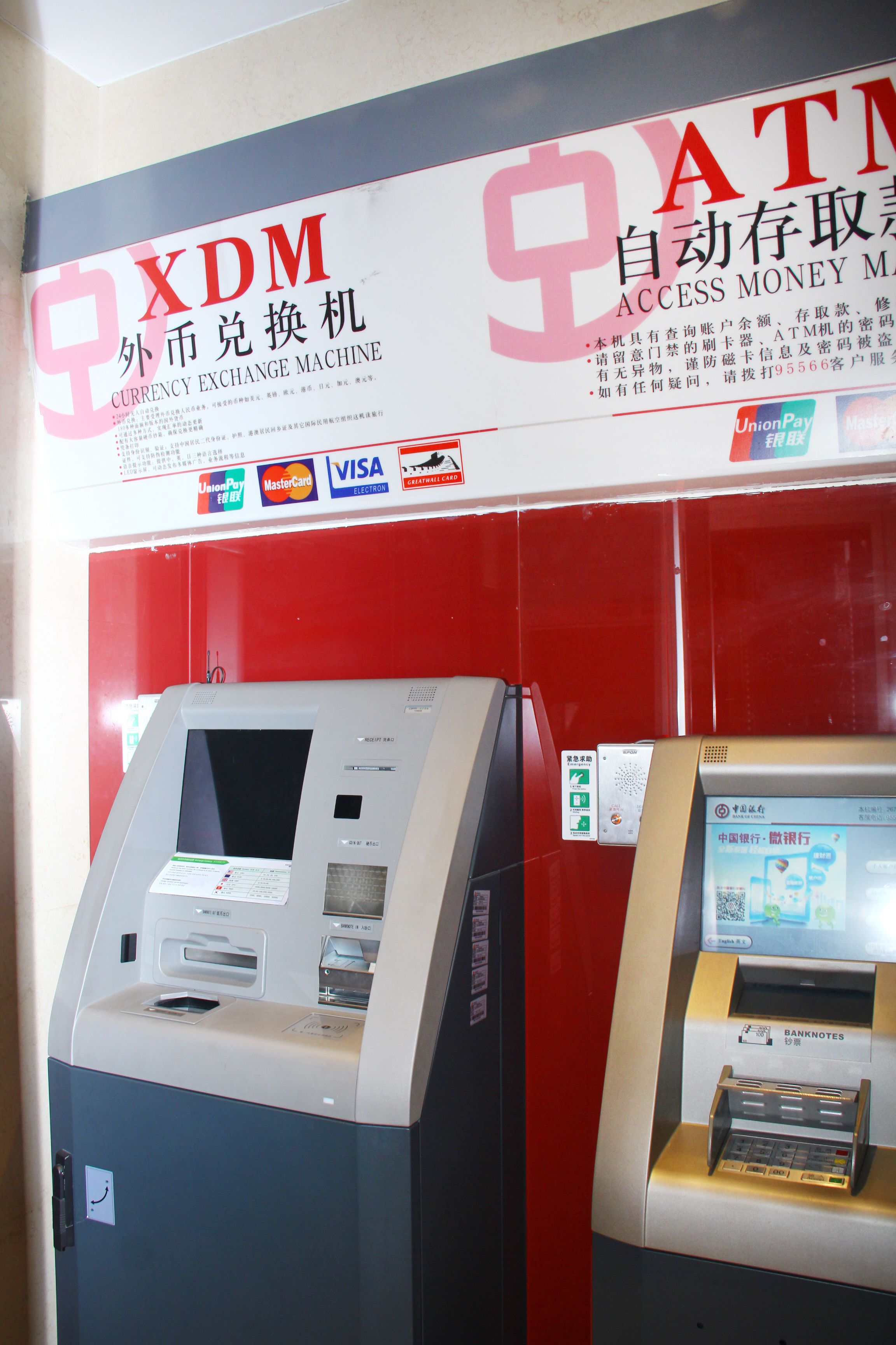 An ATM machine with a currency exchange sign above it.
