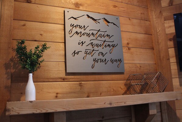 A wooden wall with a motivational quote and a white vase with green plants.