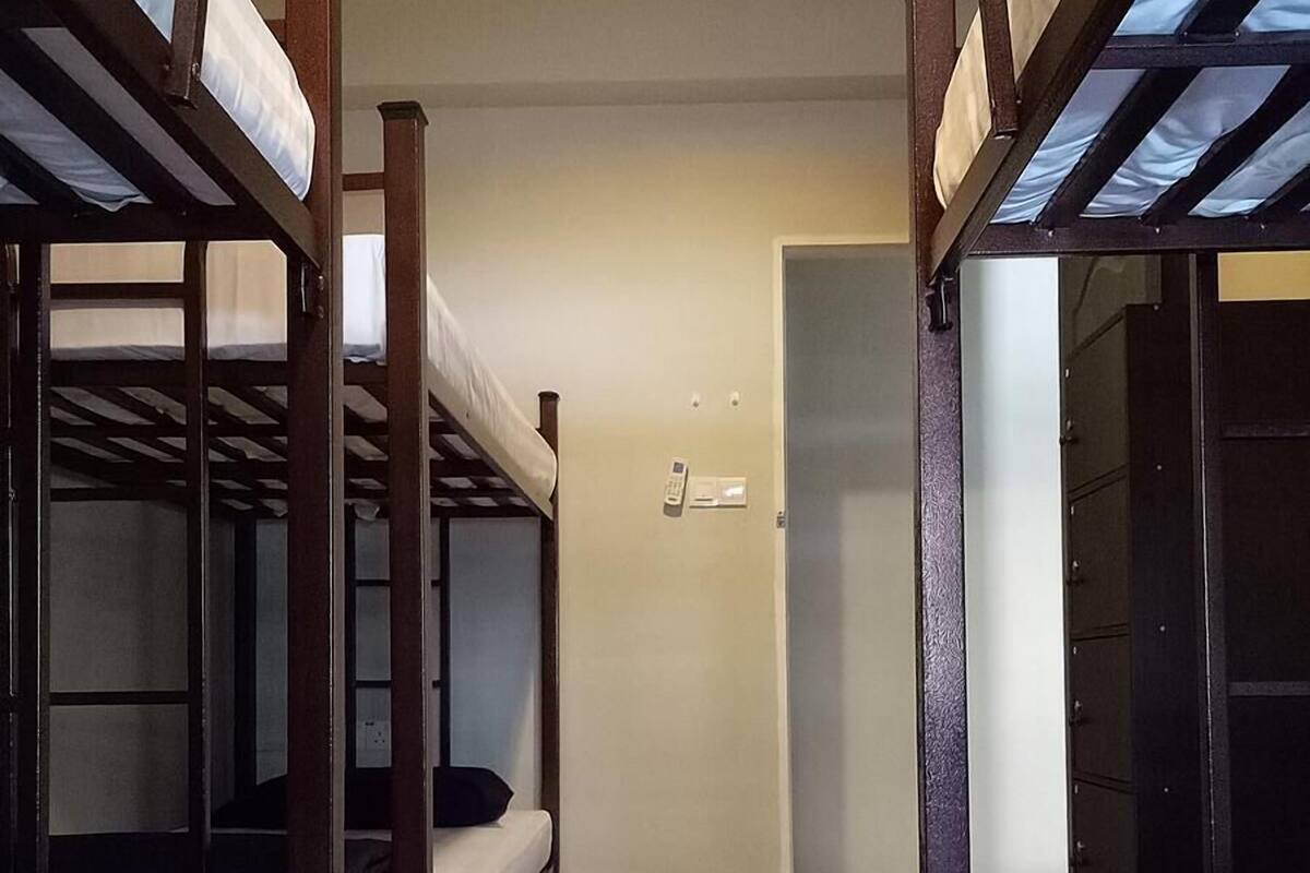 Une chambre de dortoir avec des lits superposés, une porte et un petit placard.