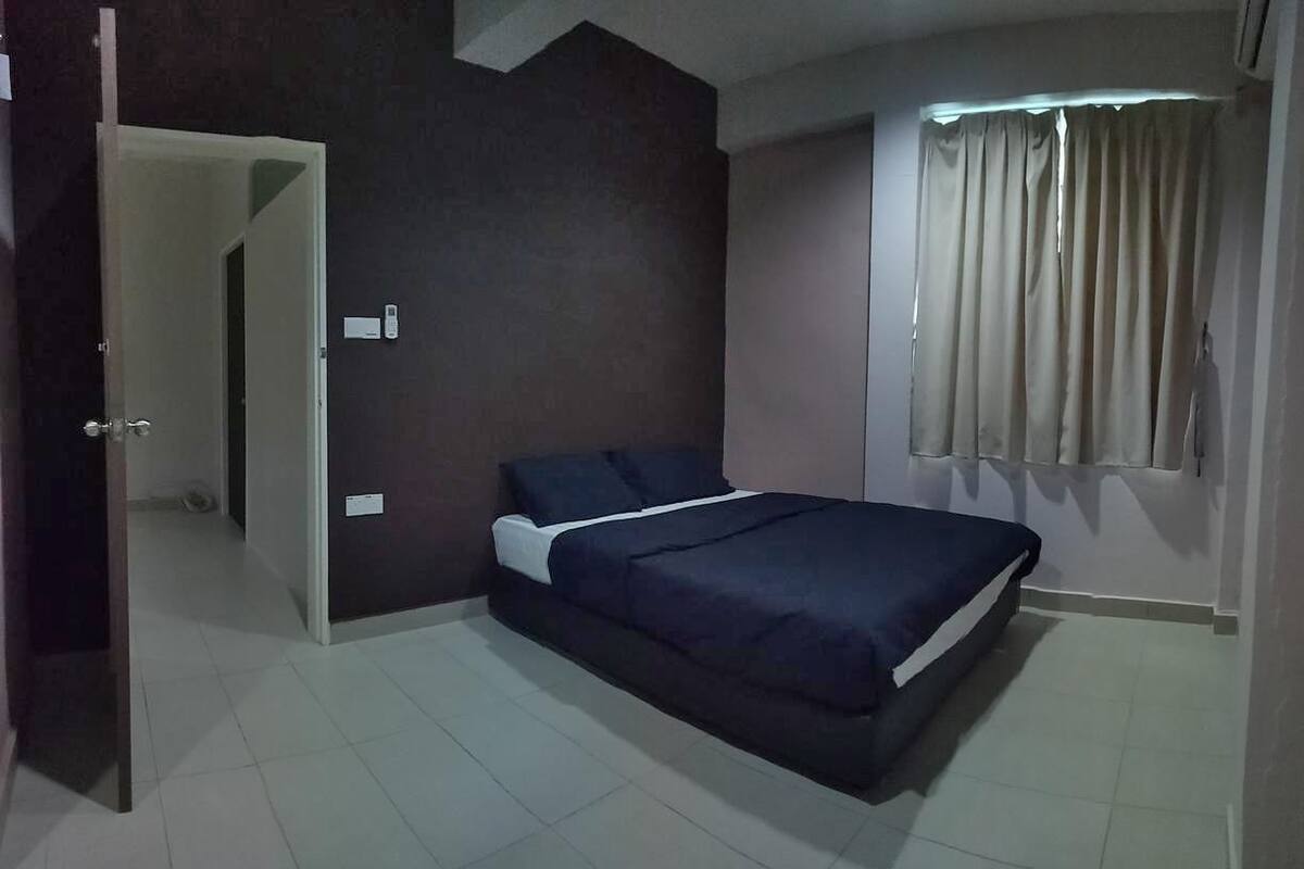 Une chambre à coucher avec un lit, une fenêtre avec des rideaux et une porte donnant sur une autre pièce.