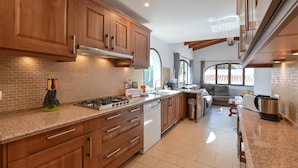 A modern kitchen with wooden cabinets, a gas stove, and a dishwasher. - Casa Virginia 6 pax - Javea, Costa Blanca (Javea)