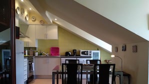 Une cuisine compacte avec un coin repas, comprenant un réfrigérateur, une cuisinière, un four à micro-ondes et une petite table à manger avec des chaises.