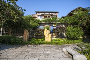 A traditional building with a tiled roof, surrounded by lush greenery and stone pathways.