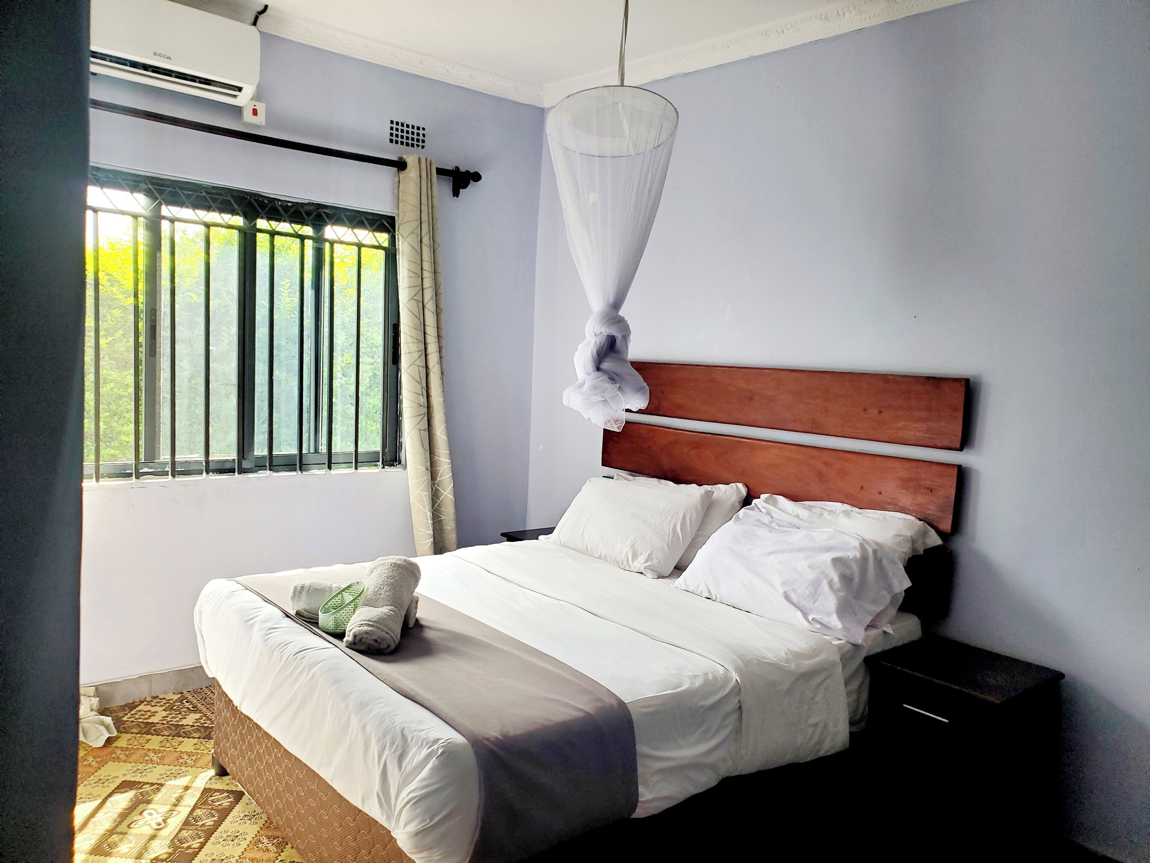A neatly made bed with white linens, a wooden headboard, and a bedside table with a black nightstand.
