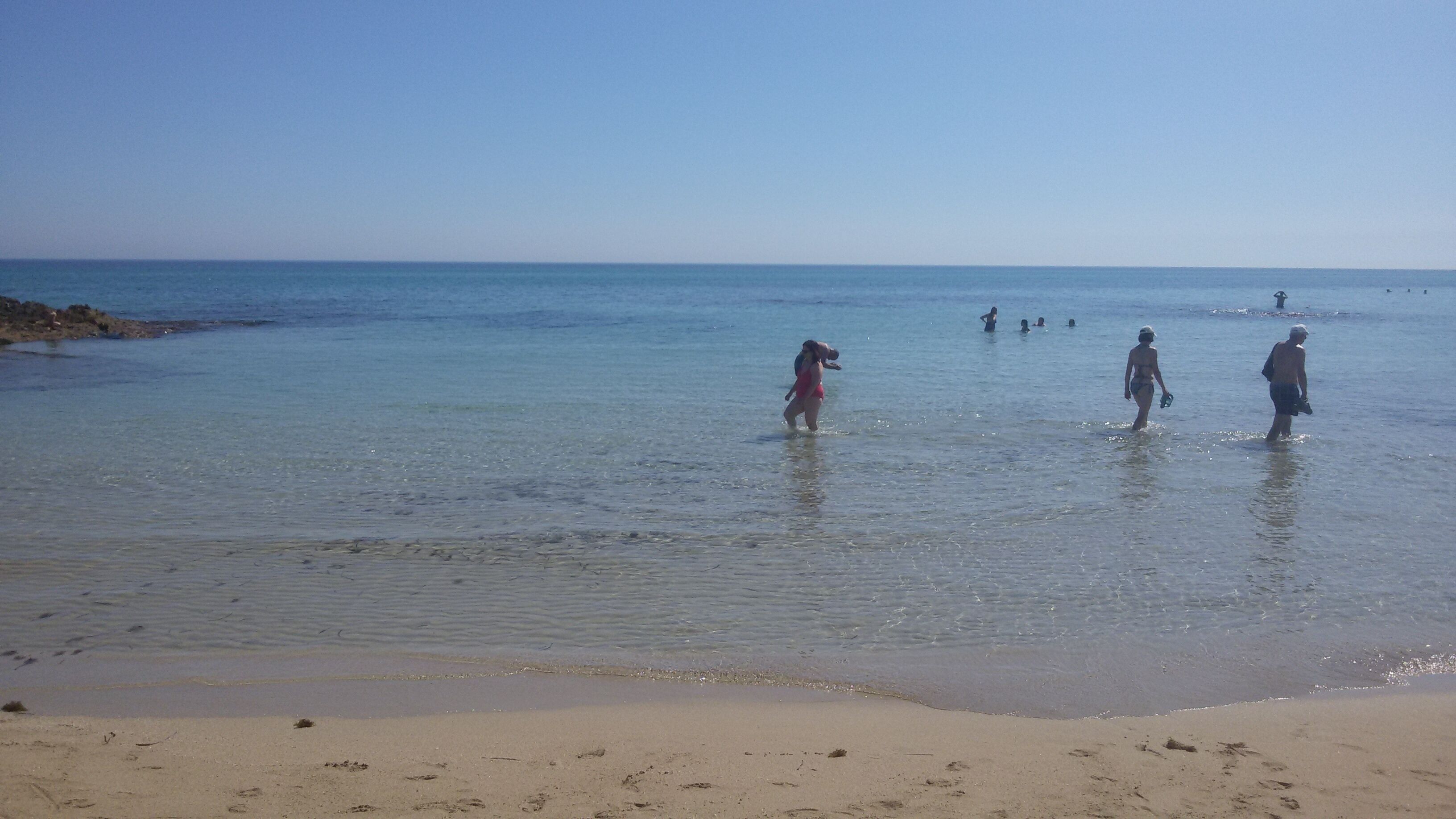 Ein Strand mit klarem Wasser und sandigem Ufer.