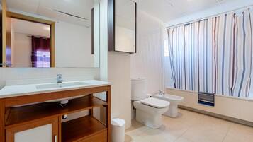 Un baño moderno con tocador de madera, un espejo grande, inodoro y bidé.