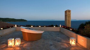 Une terrasse sur le toit dotée d’un jacuzzi, d’un sol en pierre et offrant une vue sur la mer.