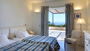 Une chambre d’hôtel avec deux lits, un bureau, une chaise et une vue sur la mer.