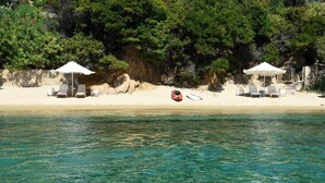 Une plage avec une eau d’un bleu limpide, des chaises longues et des parasols.