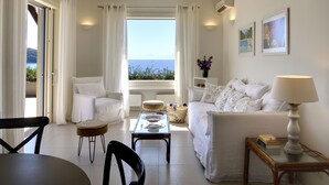 Un salon moderne avec un canapé, une table basse et une lampe. De grandes fenêtres offrent une vue sur la mer.