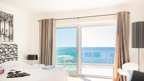 A hotel room with a bed, a desk, a chair, a table, and a view of the sea. - Luxury Villa with infinity pool and breathtaking sea view (New Prices) (Urbanização Ponta da Gaivota, Lagos)