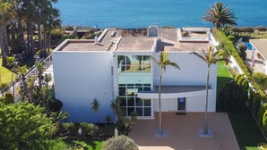 A modern building with a flat roof, large windows, and a view of the sea. - Luxury Villa with infinity pool and breathtaking sea view (New Prices) (Urbanização Ponta da Gaivota, Lagos)