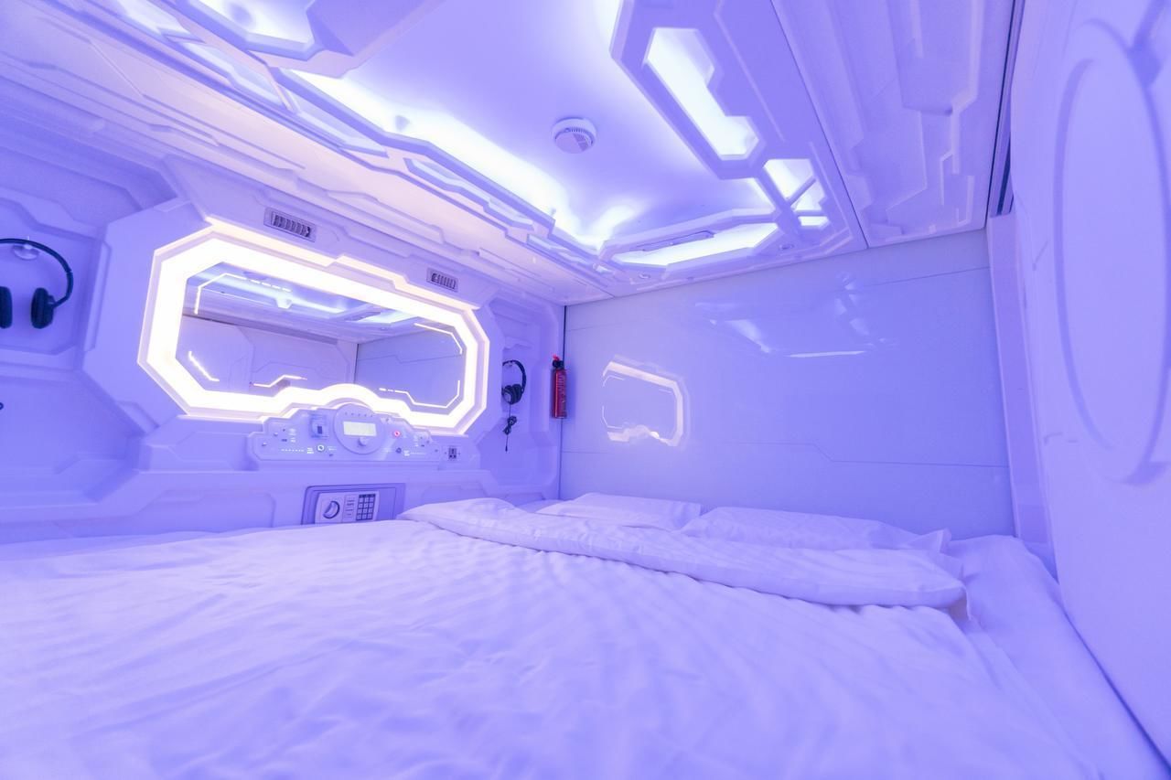 Una habitación futurista con cama, paneles de control y una ventana hexagonal.