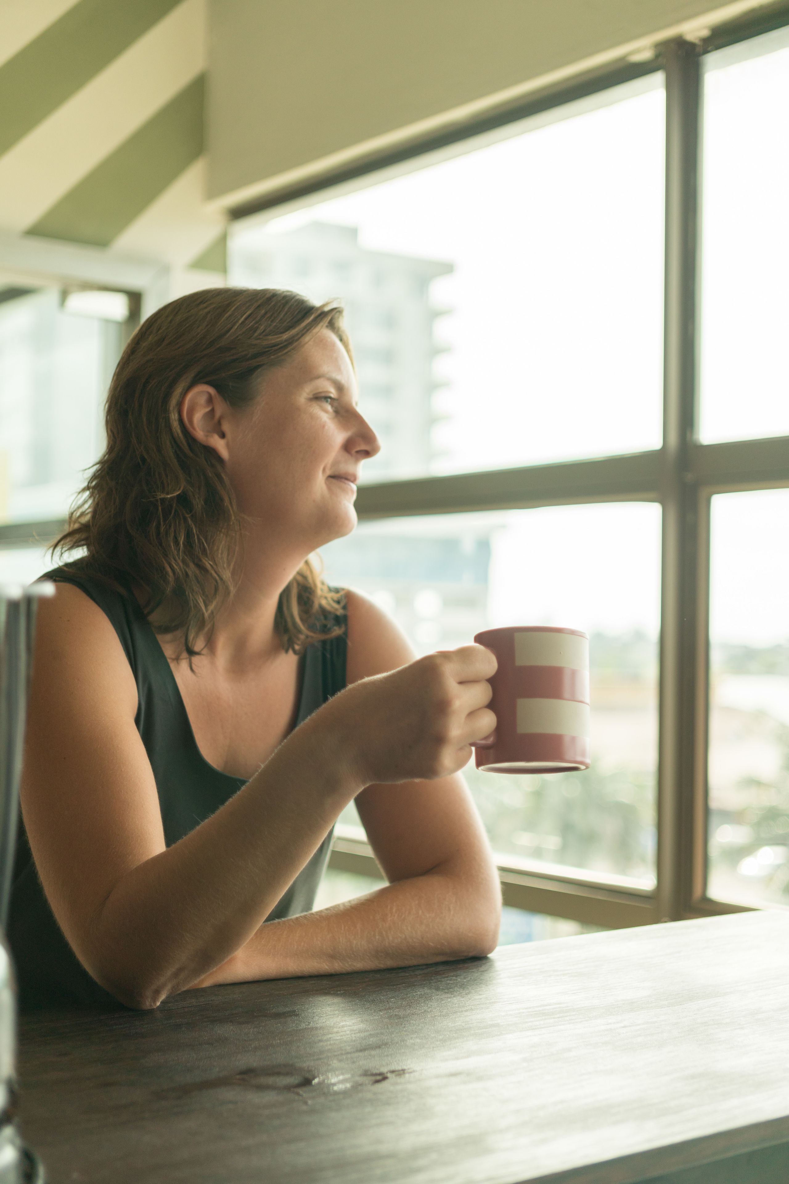 Una persona sentada junto a una ventana con vistas a edificios.