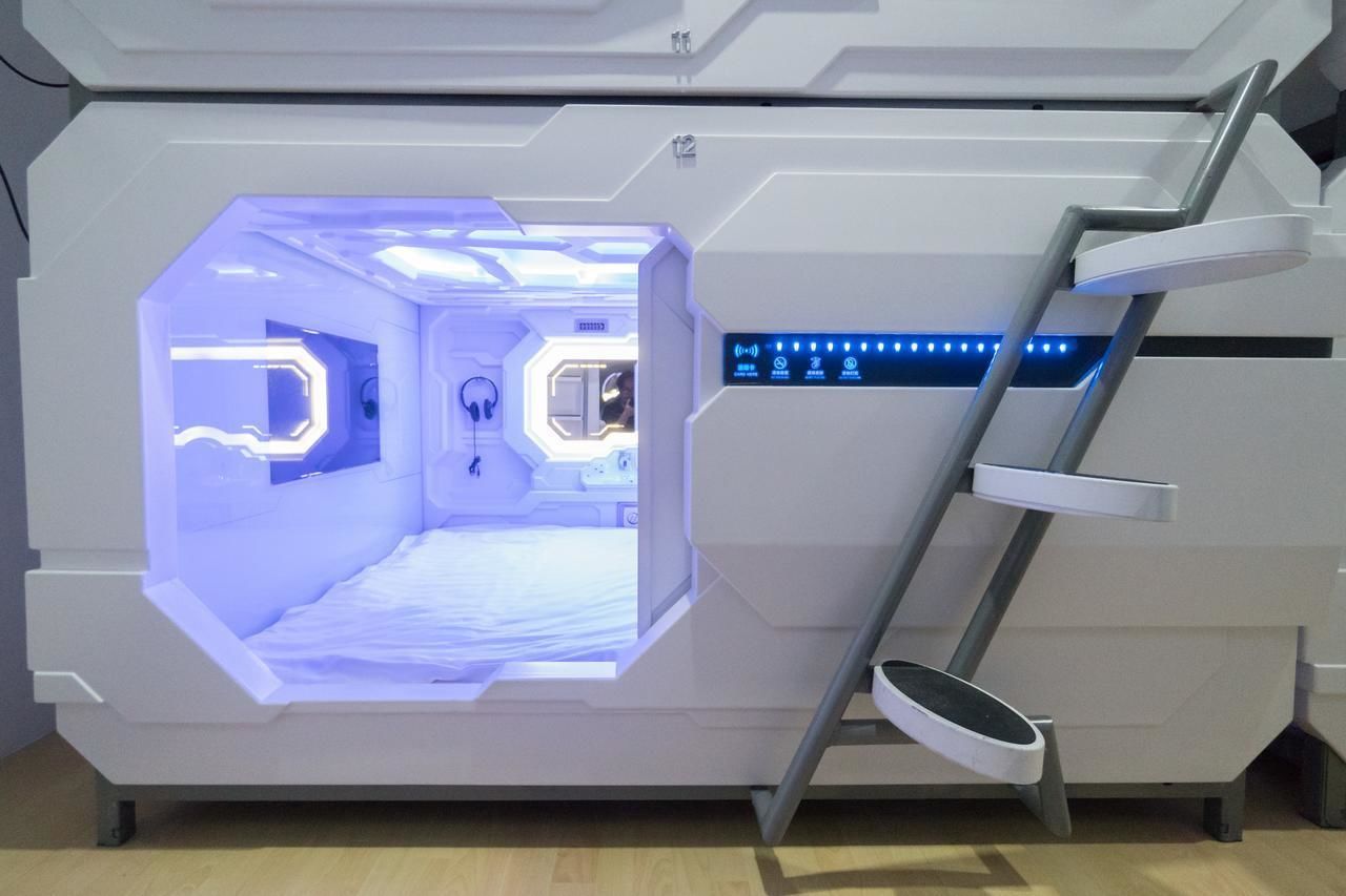 A futuristic room with a central hexagonal window, a control panel with illuminated buttons, and a ladder leading to a circular platform.