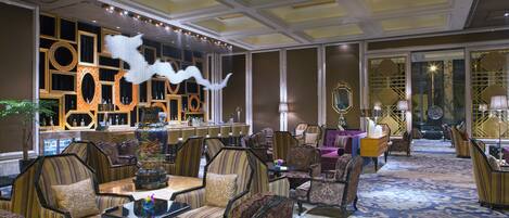 Un vestíbulo amplio con zona de bar, espacios de asiento y paneles decorativos en la pared.