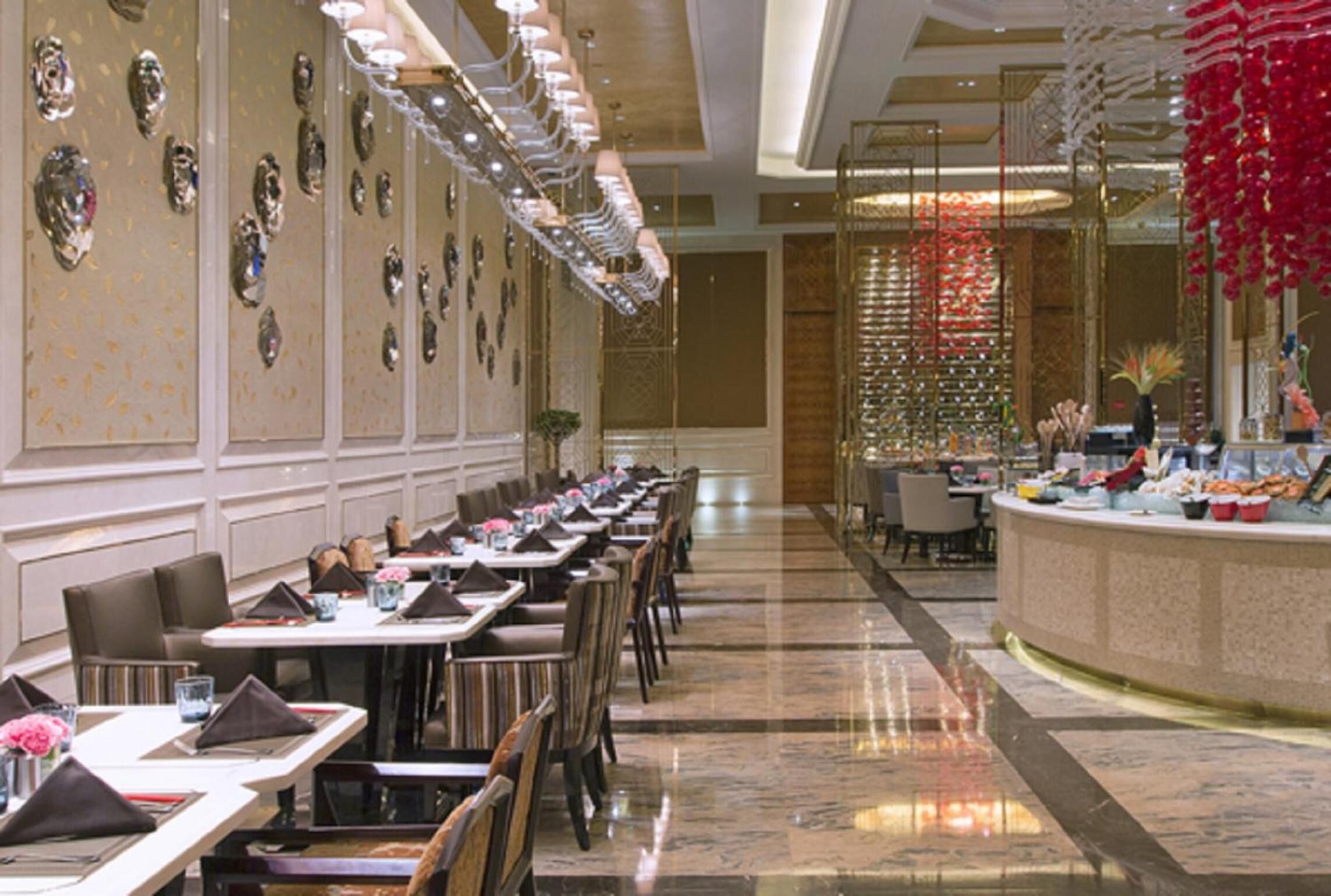 A long dining area with tables and chairs, a buffet counter, and decorative wall elements.