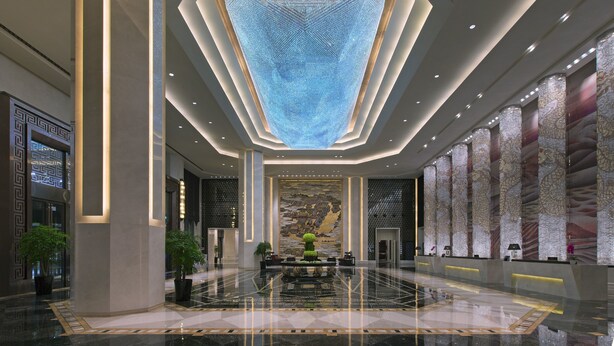 A spacious lobby with a high ceiling, a central seating area, and a large wall with intricate patterns.