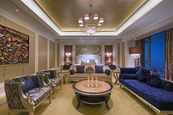 Un salón lujoso con muebles ornamentados, un candelabro y un cuadro grande en la pared.