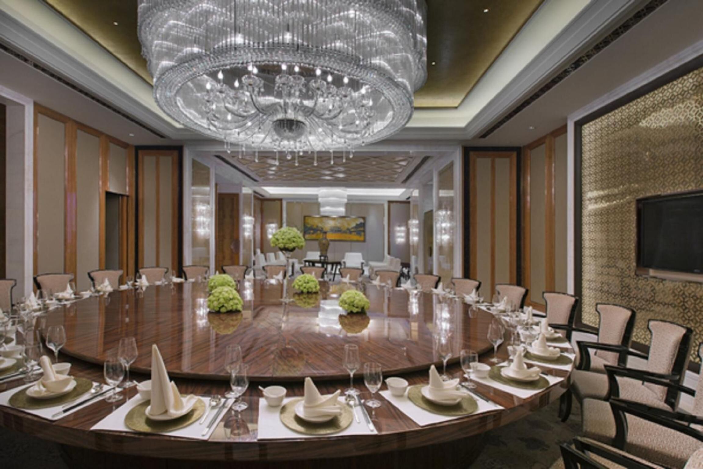 A conference room with a large round table, chairs, and a chandelier.