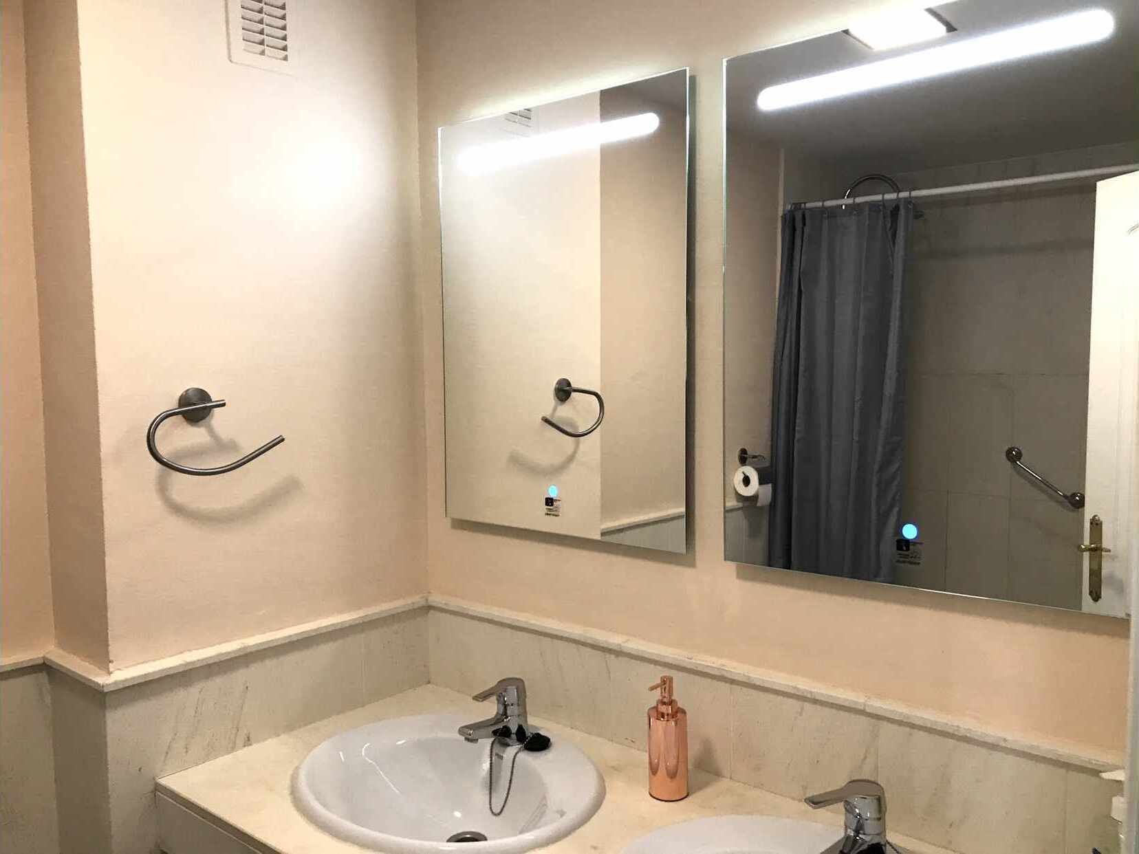 Un bagno con due lavandini, uno specchio e una tenda per la doccia.