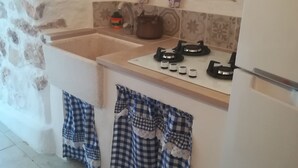 Eine Küche mit Steinwand, Spüle, Herd und karierten Topflappen, die an der Wand hängen.