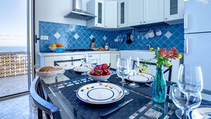 A modern kitchen with white cabinets, blue tiles, and a dining area with a table set for four.