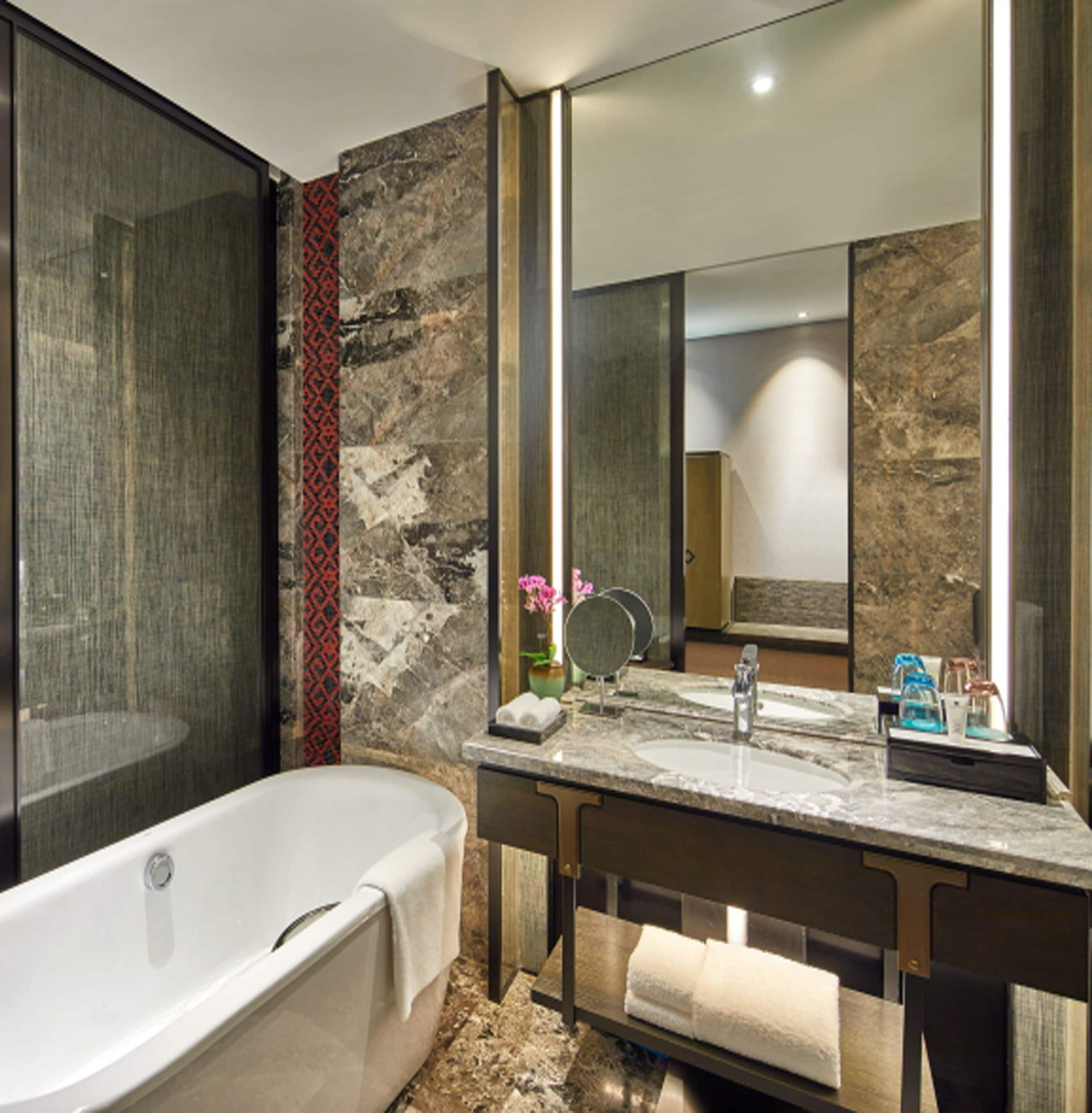 A modern bathroom with a freestanding bathtub, a marble vanity, and a large mirror.