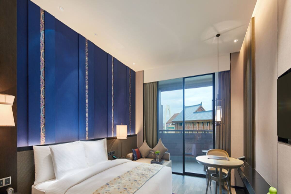 Habitación de hotel con una cama grande, un escritorio, una silla, una mesa de comedor y un televisor.