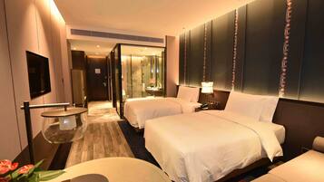A modern hotel room with two beds, a flat-screen TV, a glass table, and a large mirror.