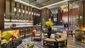 Un moderno vestíbulo de hotel con zona de bar, asientos y elementos decorativos.