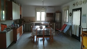 Een kleine keuken met een eettafel, stoelen en een koelkast.