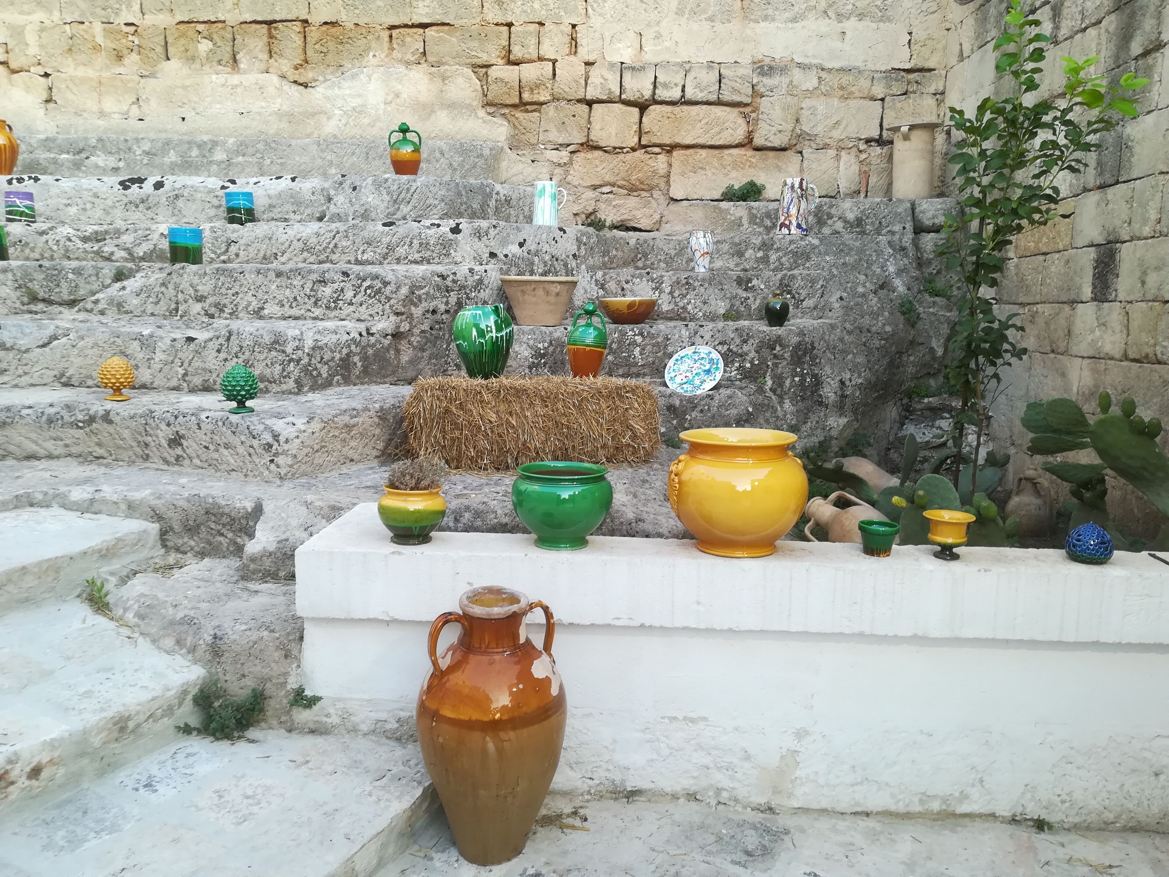 A collection of ceramic pots and vases on a stone staircase.